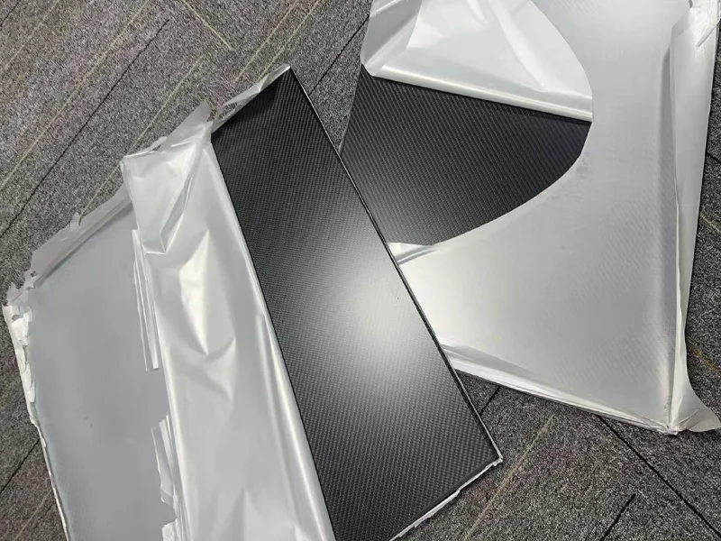 Close up of glossy carbon fiber sheet showing mirror like reflection and woven pattern