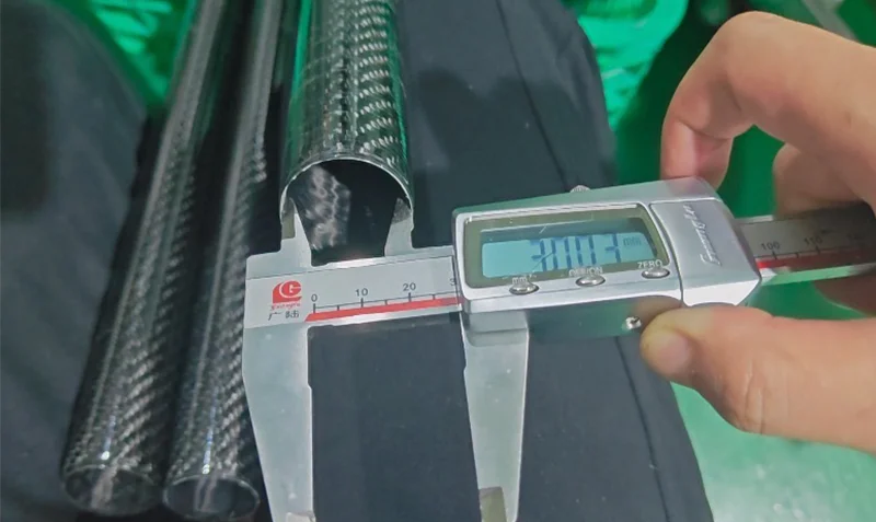 Quality inspector measuring carbon fiber tube dimensions with digital calipers in ISO 9001 certified facility