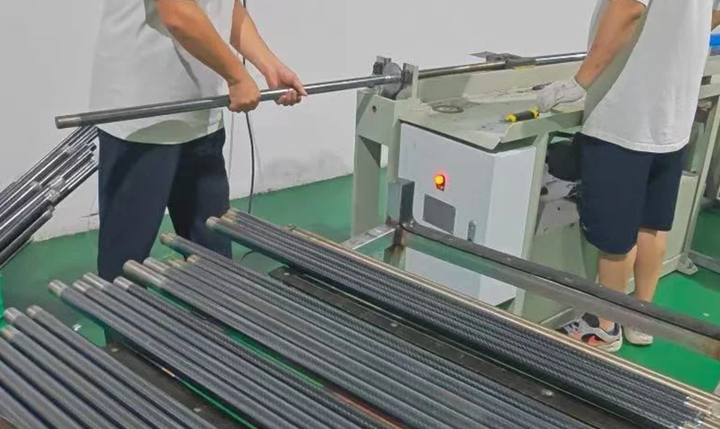 Roll-wrapping T300 twill carbon fiber tubes on mandrels in YTCarbon factory with curing oven in background